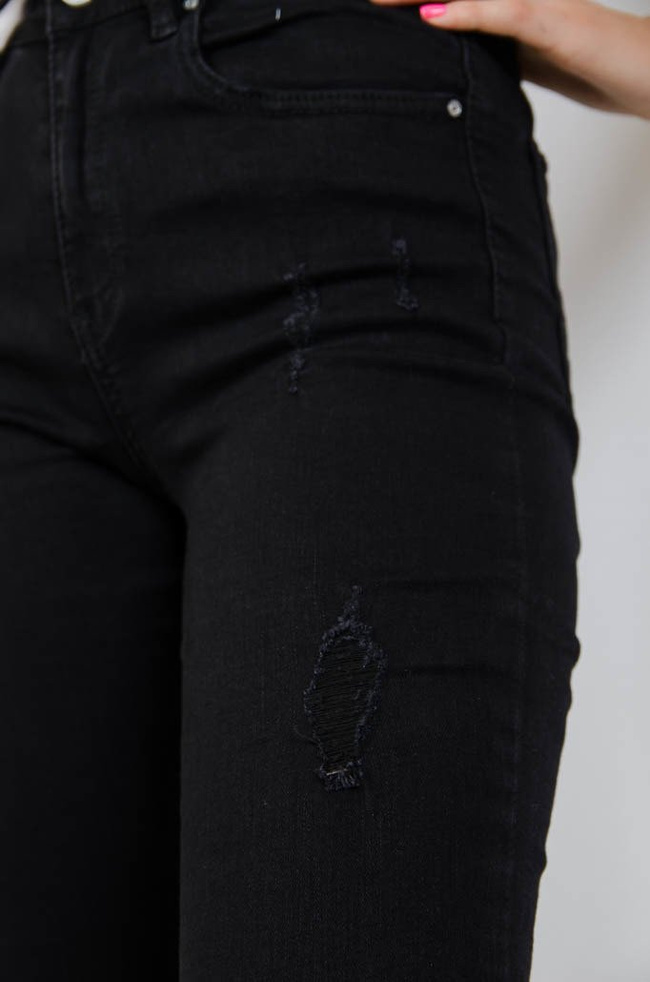Czarne jeansowe spodnie z przetarciami oraz szarpaniem na dole nogawki