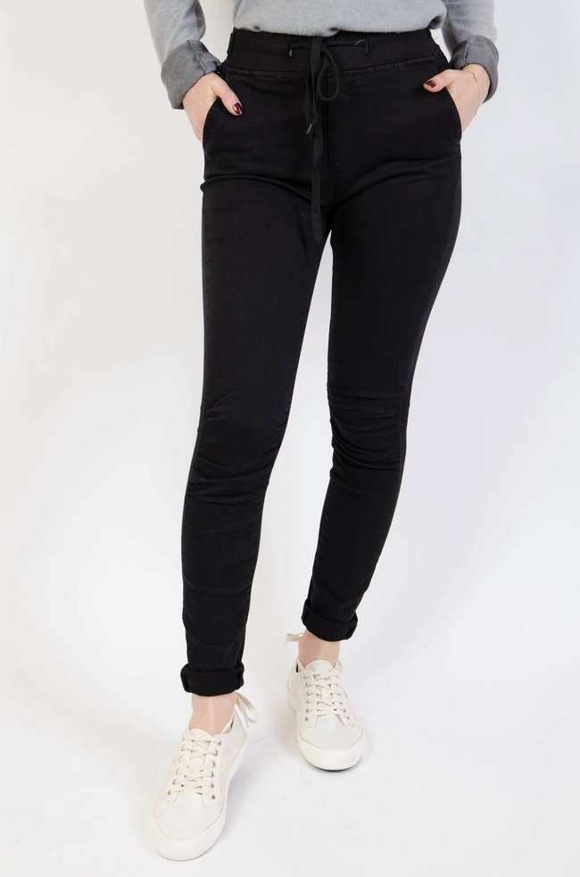 Czarne spodnie jeansowe z gumą w pasie oraz marszczeniem na kolanach