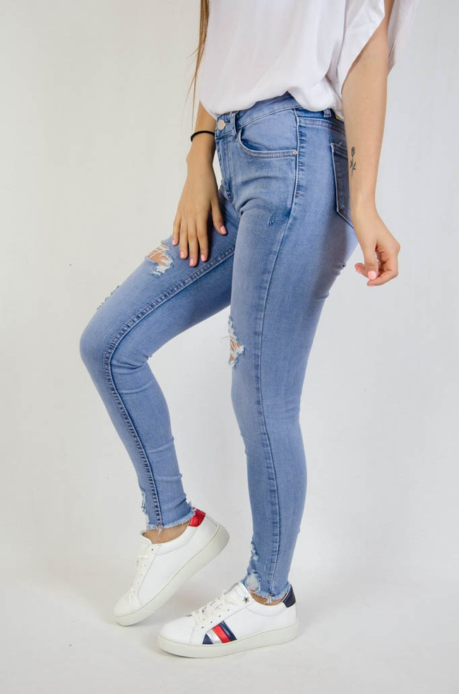 Jasne spodnie jeansowe z dziurami oraz szarpaniem przy nogawce