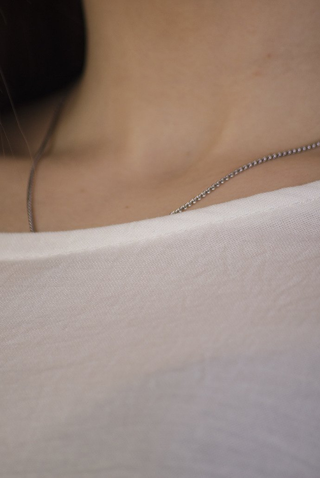 Biała bluzka z wycięciem na plecach oraz koralikami na ramionach