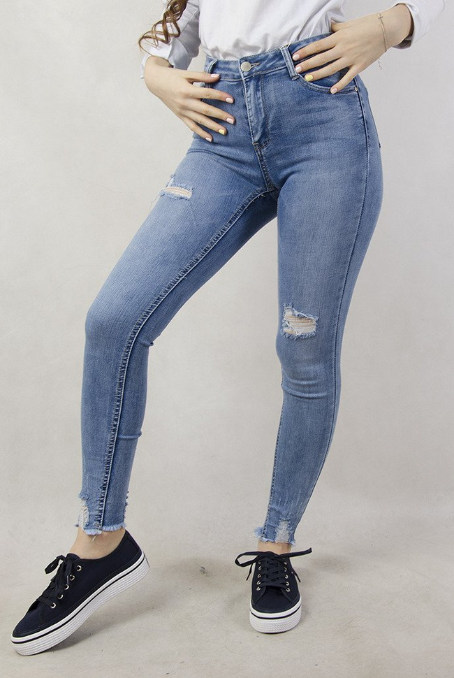 Jasne spodnie jeansowe z dziurami oraz przetarciami