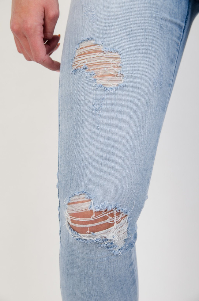 Jasne spodnie jeansowe z dziurami i zamkiem na nogawce