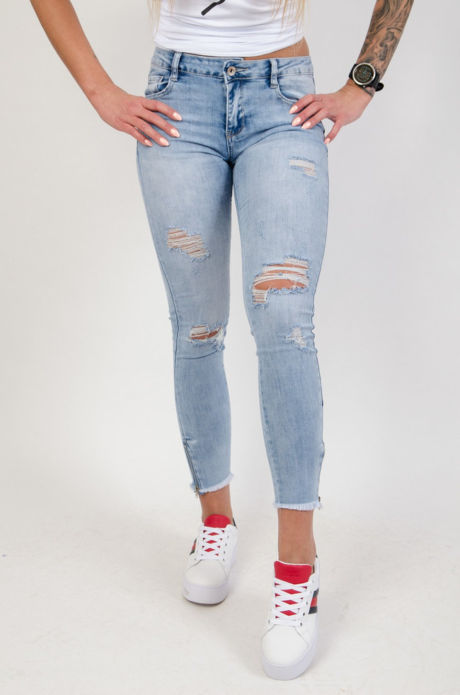 Jasne spodnie jeansowe z dziurami i zamkiem na nogawce