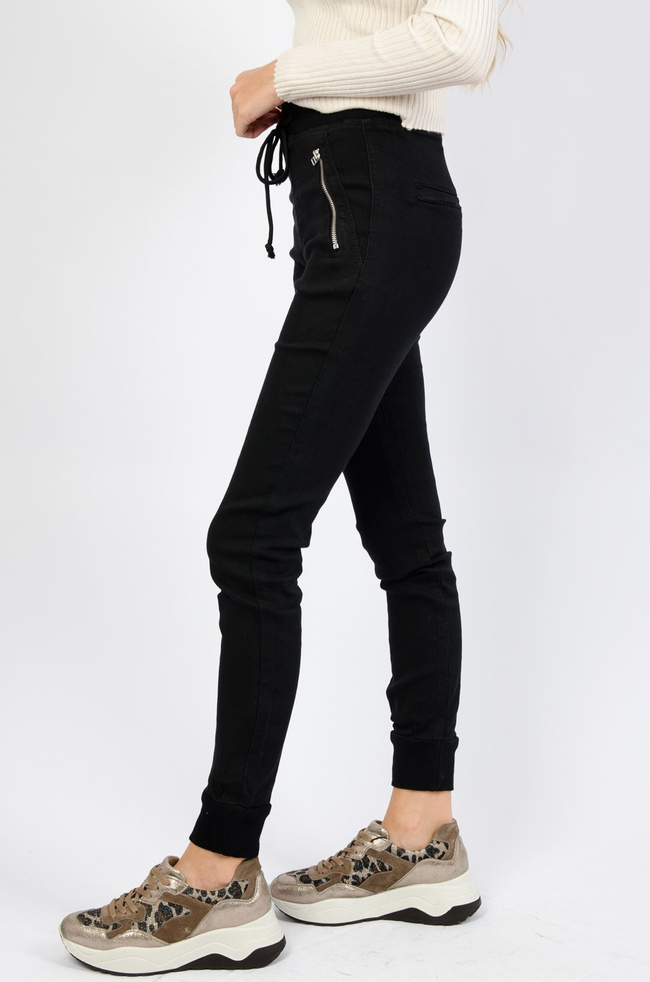 Czarne spodnie ze ściągaczem na dole oraz gumką w pasie