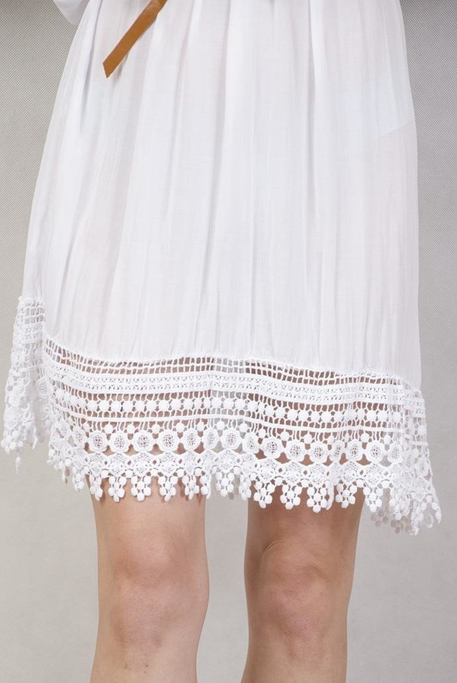 Biała sukienka z koronką przy rękawach.