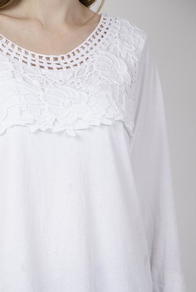 Biała bluzka z ażurowymi zdobieniami przy dekolcie oraz ze ściągaczem na dole