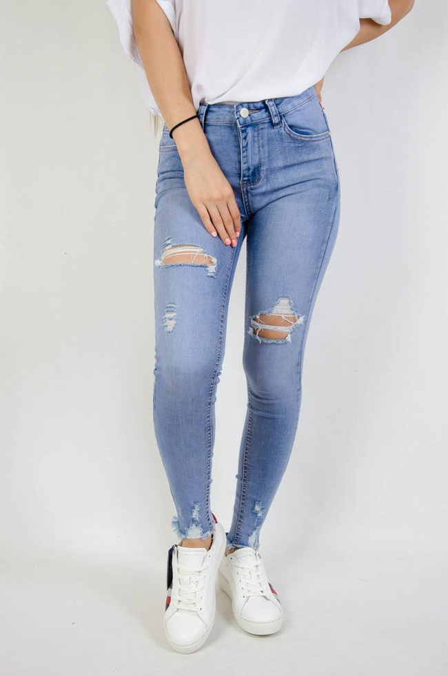 Jasne spodnie jeansowe z dziurami oraz szarpaniem przy nogawce