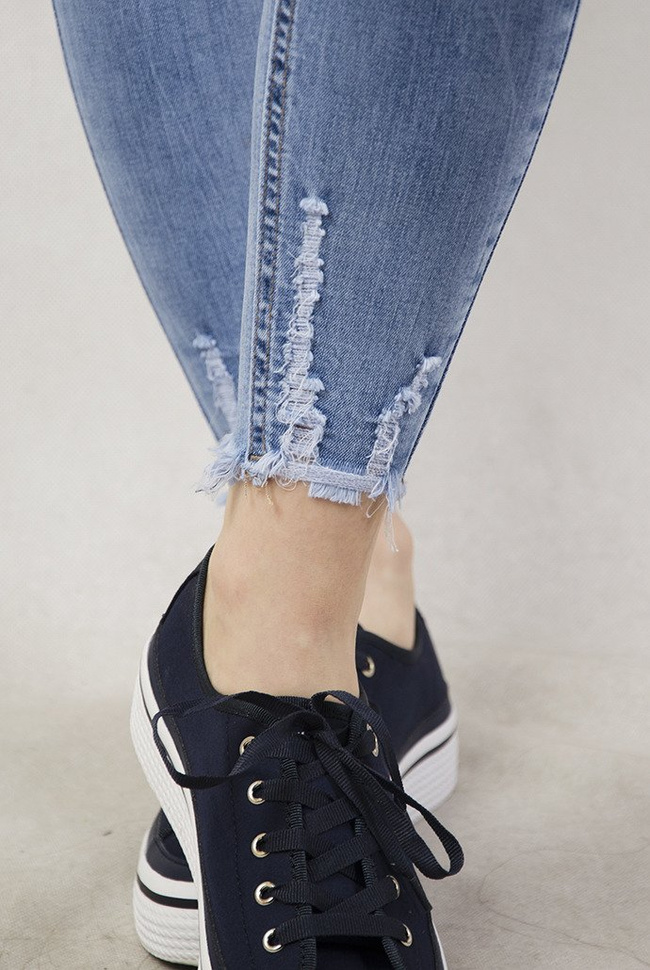 Jasne spodnie jeansowe z szarpaniem przy nogawce