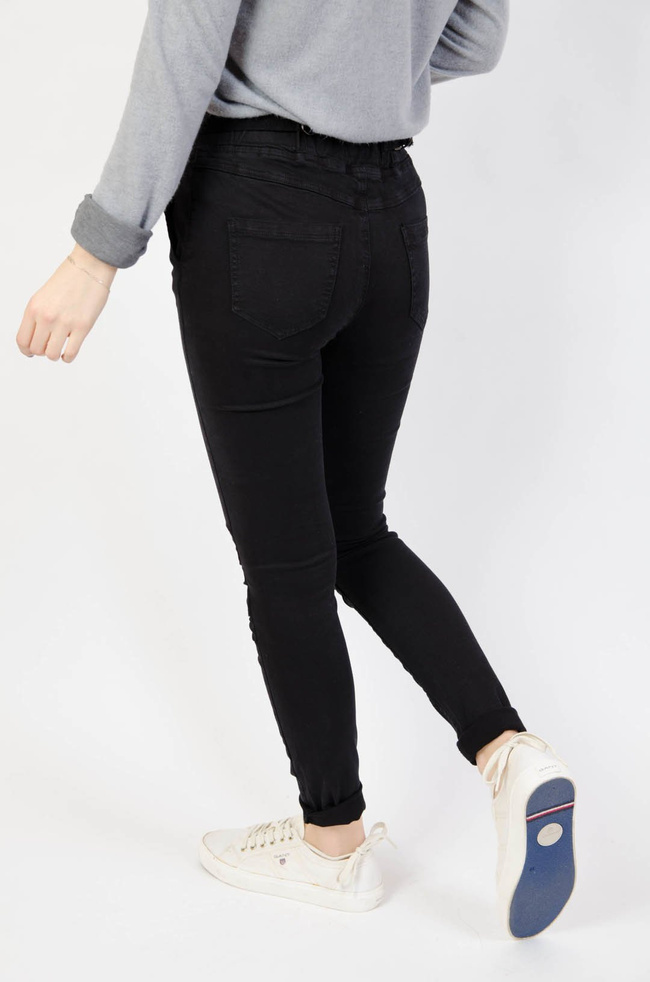 Czarne spodnie jeansowe z gumą w pasie oraz marszczeniem na kolanach