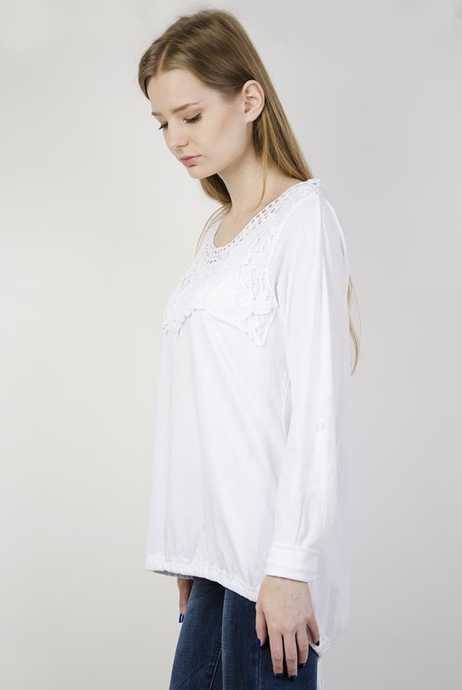 Biała bluzka z ażurowymi zdobieniami przy dekolcie oraz ze ściągaczem na dole