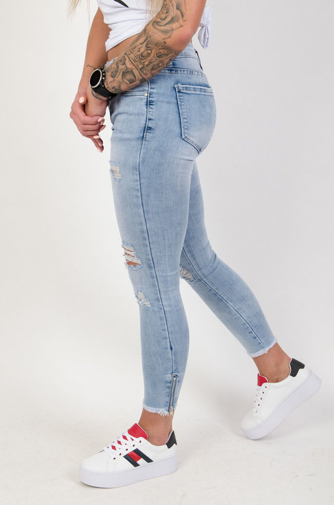 Jasne spodnie jeansowe z dziurami i zamkiem na nogawce