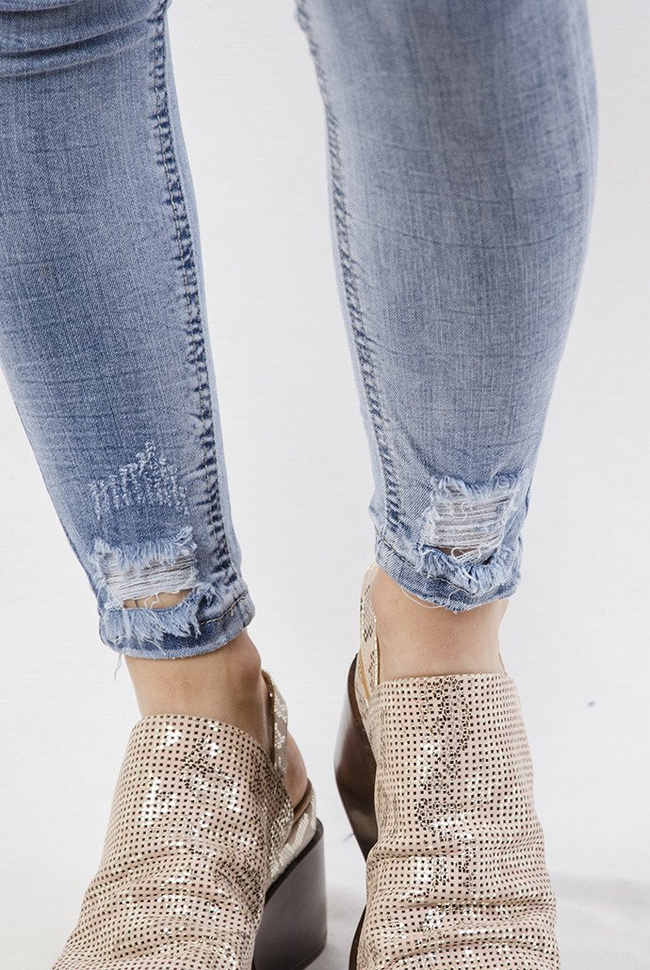 Jasne spodnie jeansowe z przetarciami na dole nogawki