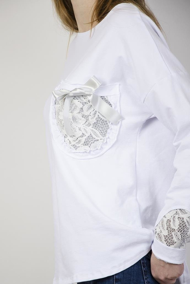 Biała bluzka z kokardką przy kieszonce i zdobieniami przy rękawach