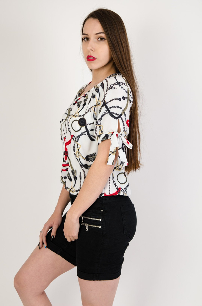 Biała bluzka z gumą na dole i wzorem pasków oraz łańcuszków