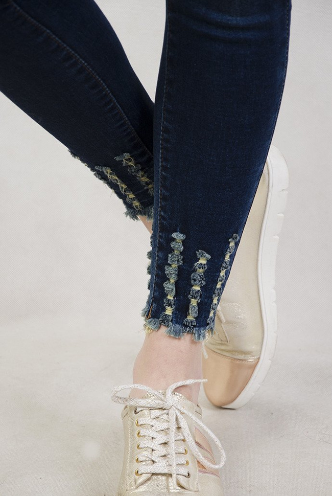 Ciemne spodnie jeansowe z wysokim stanem oraz szarpaniami przy nogawce