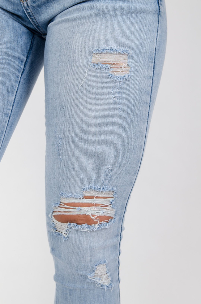 Jasne spodnie jeansowe z dziurami i zamkiem na nogawce