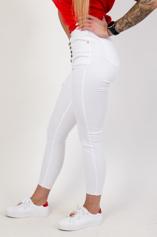 Białe spodnie jeansowe z przetarciami zapinane na guziki