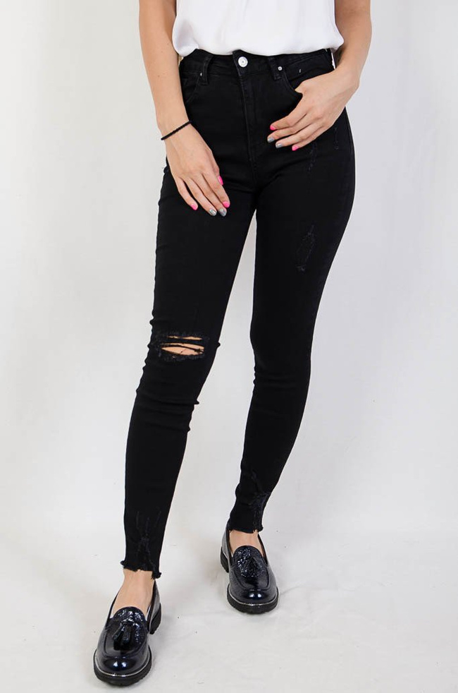 Czarne jeansowe spodnie z przetarciami oraz szarpaniem na dole nogawki