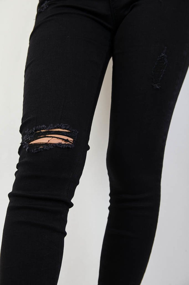 Czarne jeansowe spodnie z przetarciami oraz szarpaniem na dole nogawki