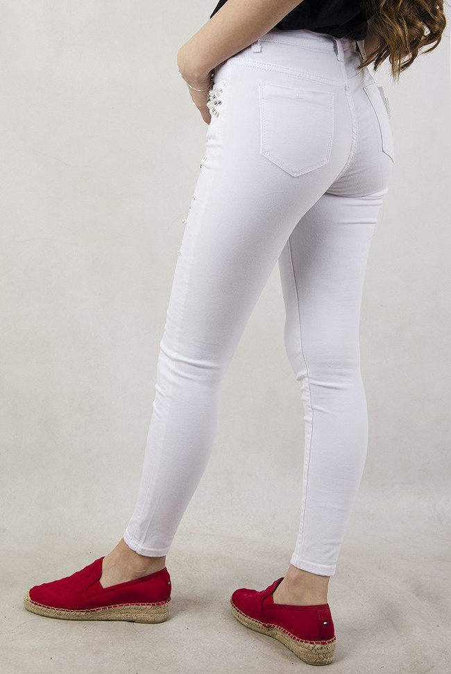 Białe spodnie z przetarciami oraz koralikami