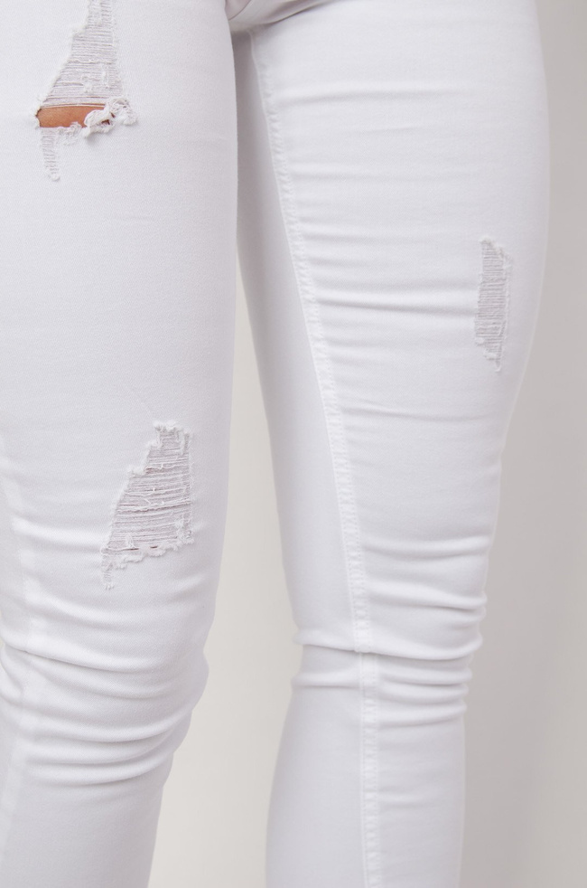 Białe spodnie jeansowe z przetarciami zapinane na guziki