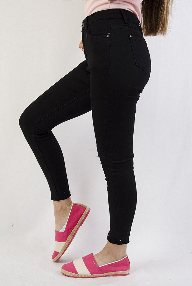 Czarne spodnie z przetarciami oraz szarpaniem przy nogawce