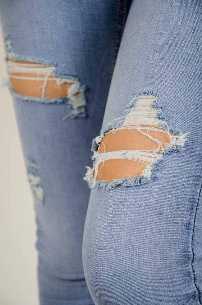 Jasne spodnie jeansowe z dziurami oraz szarpaniem przy nogawce