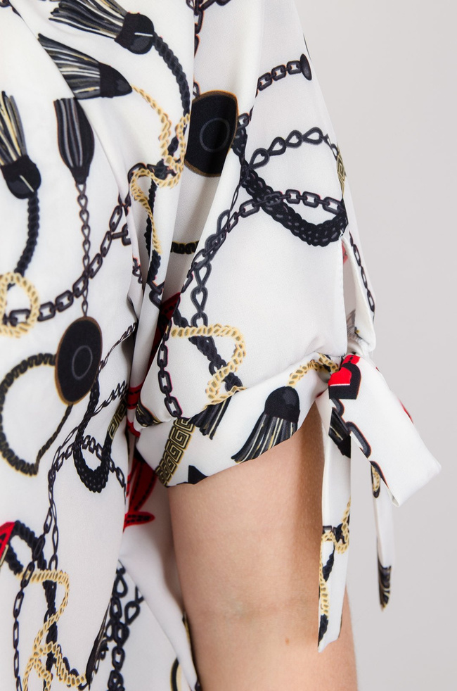 Biała bluzka z gumą na dole i wzorem pasków oraz łańcuszków