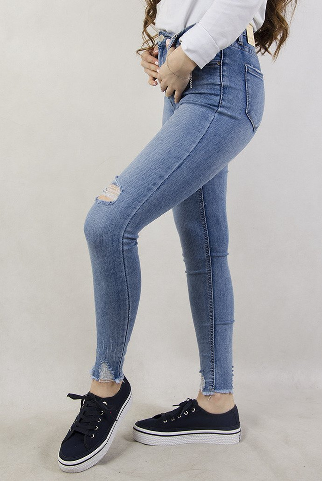 Jasne spodnie jeansowe z dziurami oraz przetarciami