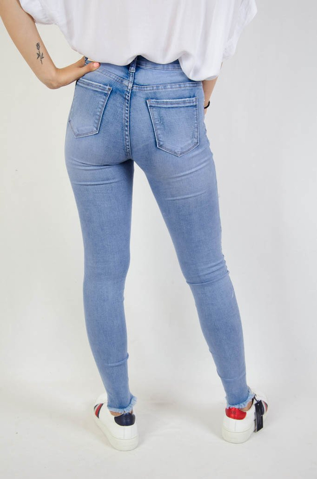 Jasne spodnie jeansowe z dziurami oraz szarpaniem przy nogawce