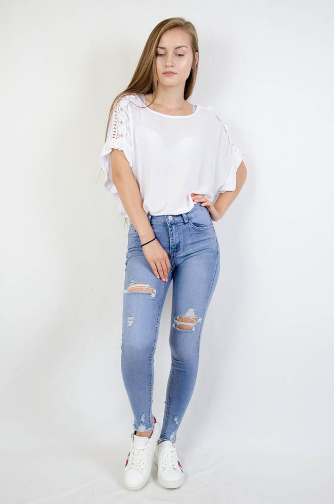 Jasne spodnie jeansowe z dziurami oraz szarpaniem przy nogawce