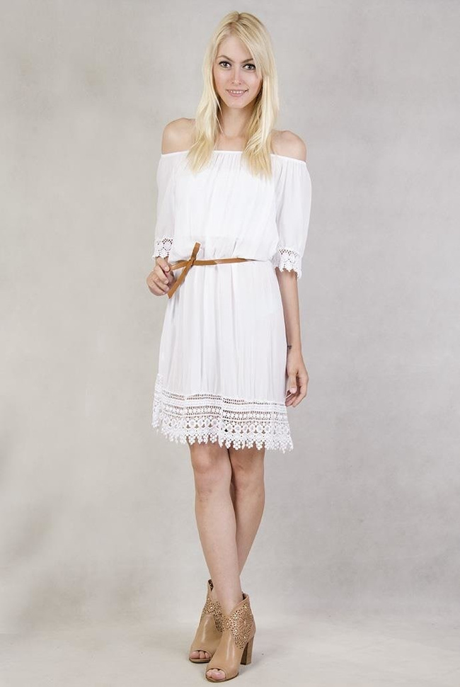 Biała sukienka z koronką przy rękawach.