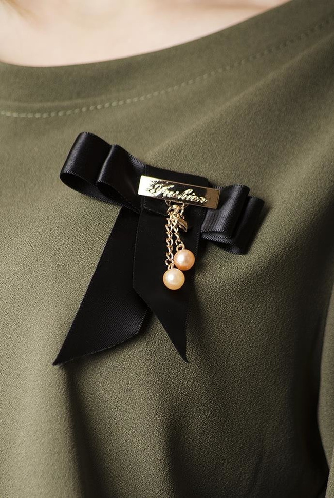 Zielona sukienka z falbankami i broszką