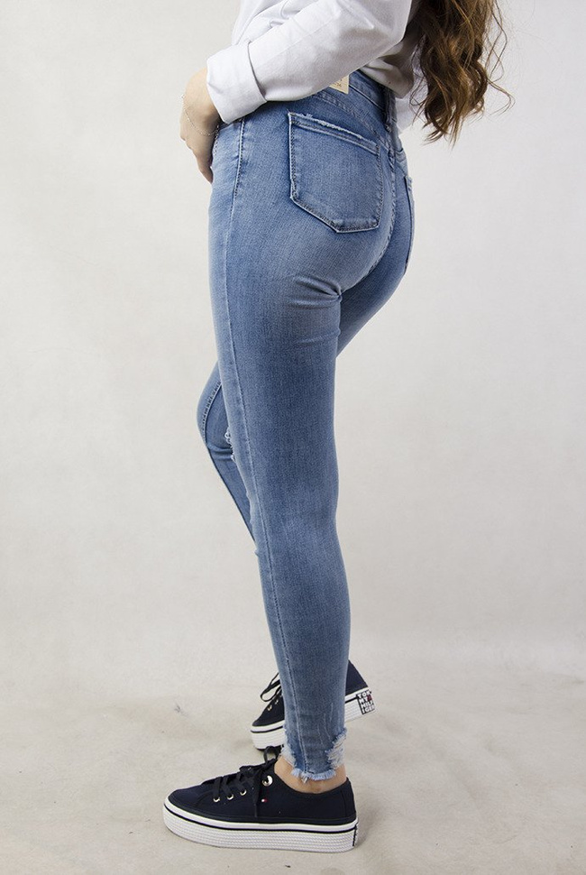 Jasne spodnie jeansowe z dziurami oraz przetarciami