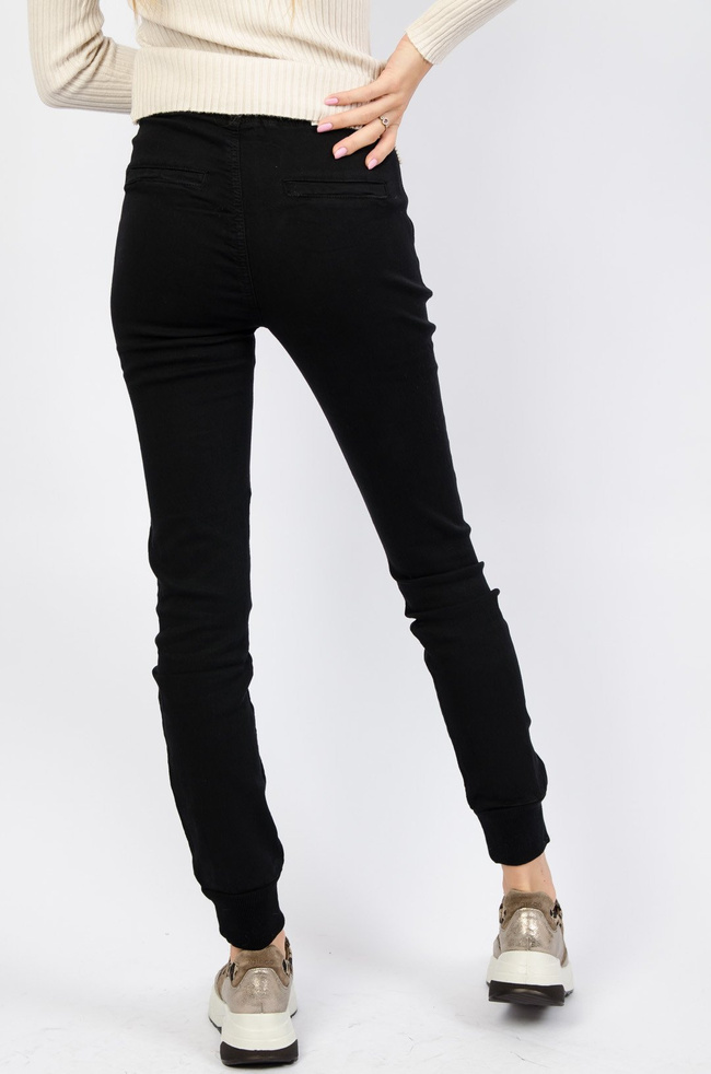 Czarne spodnie ze ściągaczem na dole oraz gumką w pasie