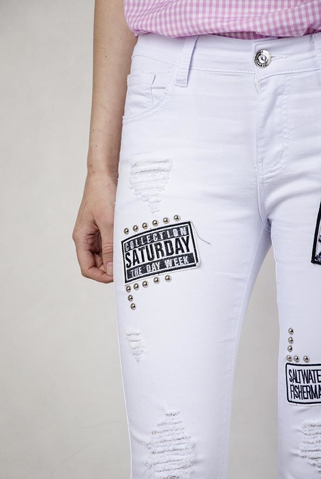 Białe spodnie jeansowe z naszywkami i dziurami