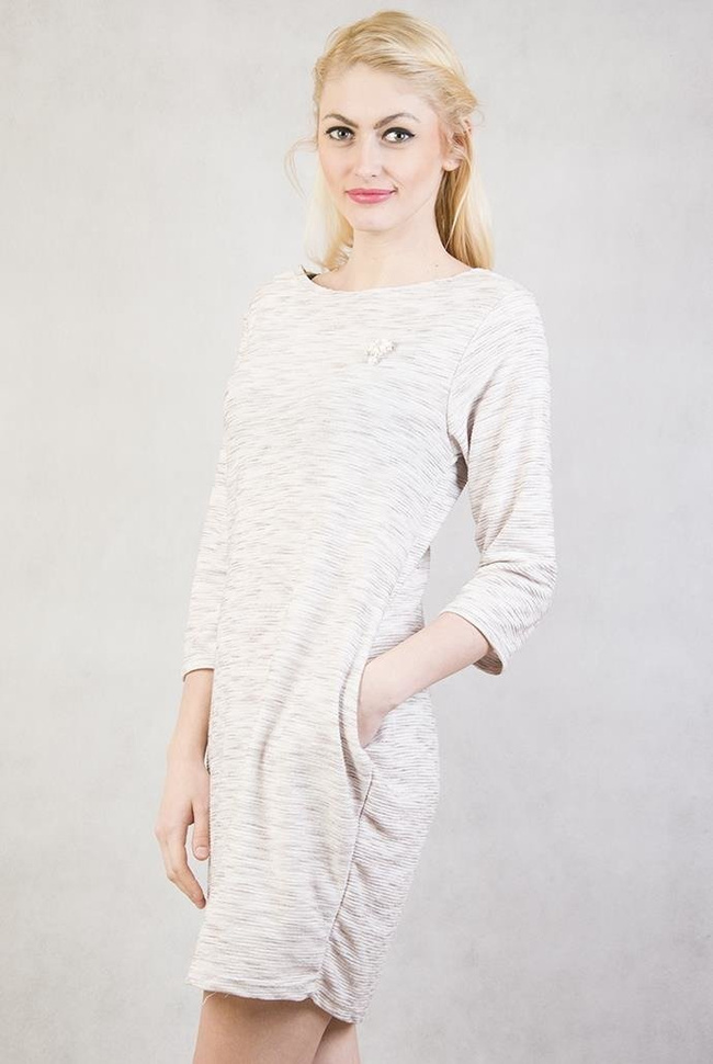 Beżowa tunika z dwoma kieszeniami oraz broszką