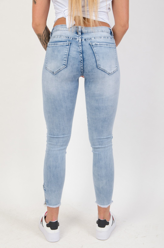 Jasne spodnie jeansowe z dziurami i zamkiem na nogawce