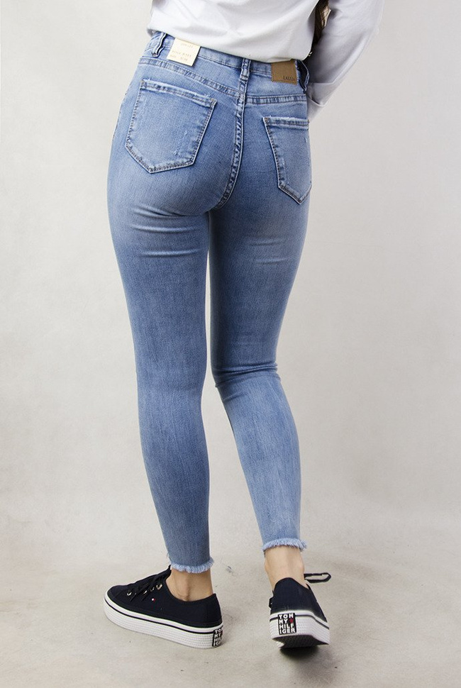 Jasne spodnie jeansowe z szarpaniem przy nogawce