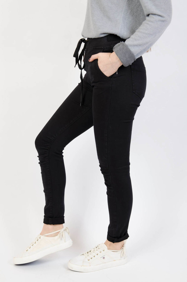 Czarne spodnie jeansowe z gumą w pasie oraz marszczeniem na kolanach