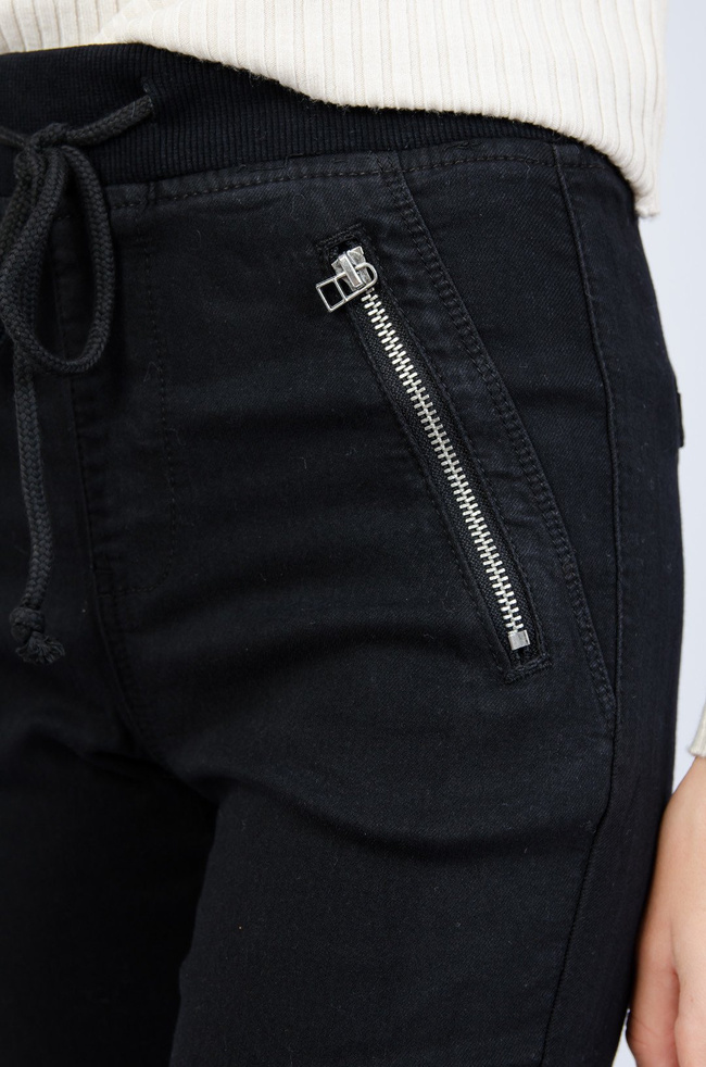 Czarne spodnie ze ściągaczem na dole oraz gumką w pasie
