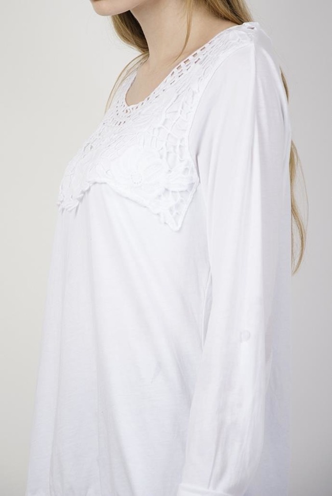 Biała bluzka z ażurowymi zdobieniami przy dekolcie oraz ze ściągaczem na dole