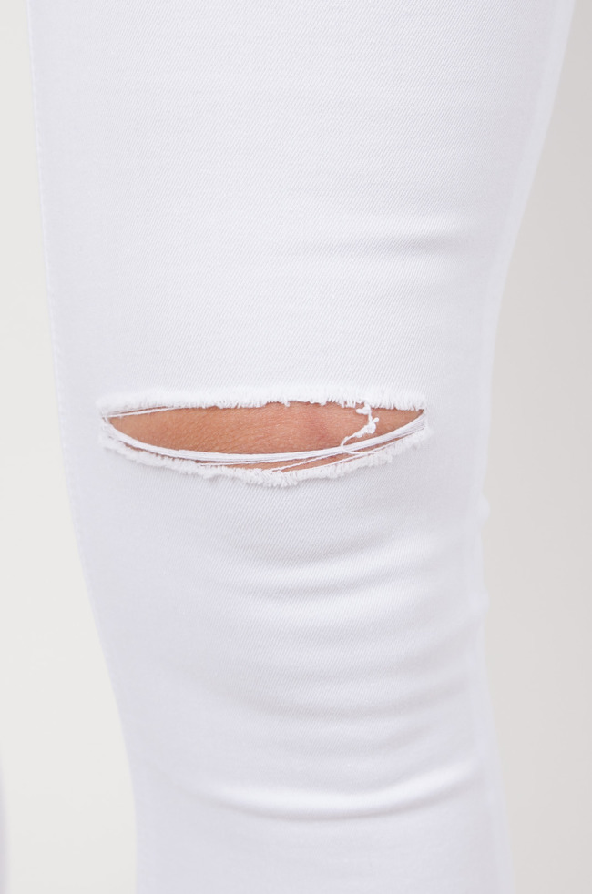 Białe dopasowane spodnie z rozcięciami na kolanach