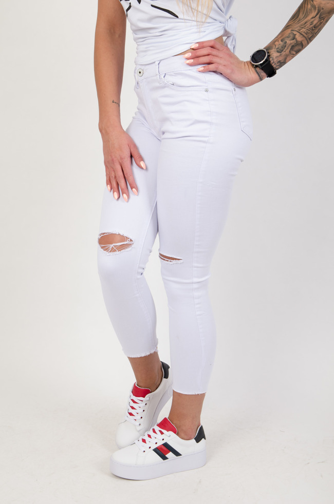 Białe przylegające spodnie z rozcięciami na kolanach