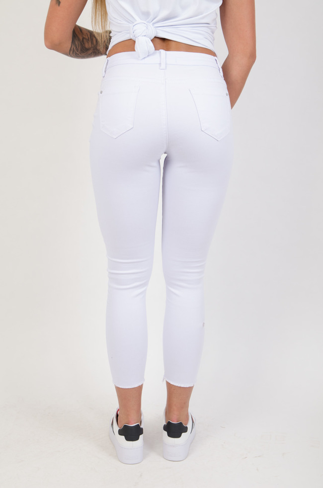 Białe przylegające spodnie z rozcięciami na kolanach