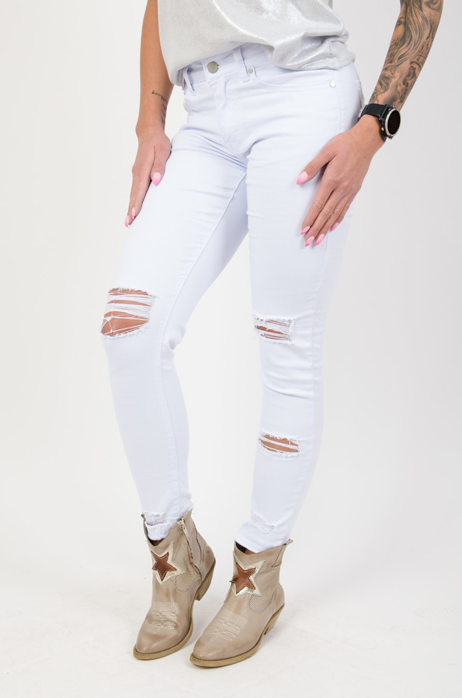 Białe spodnie jeansowe z dziurami na przodzie