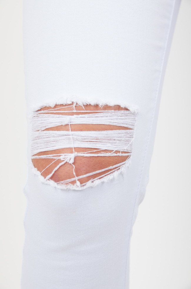 Białe spodnie jeansowe z dziurami na przodzie