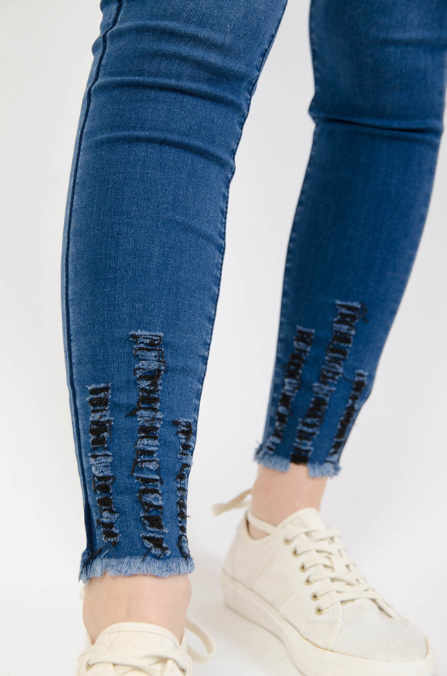 Ciemnoniebieskie spodnie jeansowe z przetarciami na dole nogawki