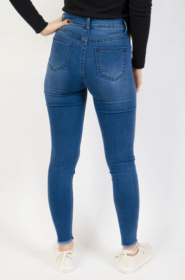 Ciemnoniebieskie spodnie jeansowe z przetarciami na dole nogawki