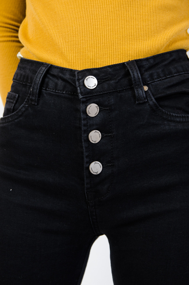 Czarne spodnie jeansowe z czterema srebrnymi guzikami na przodzie